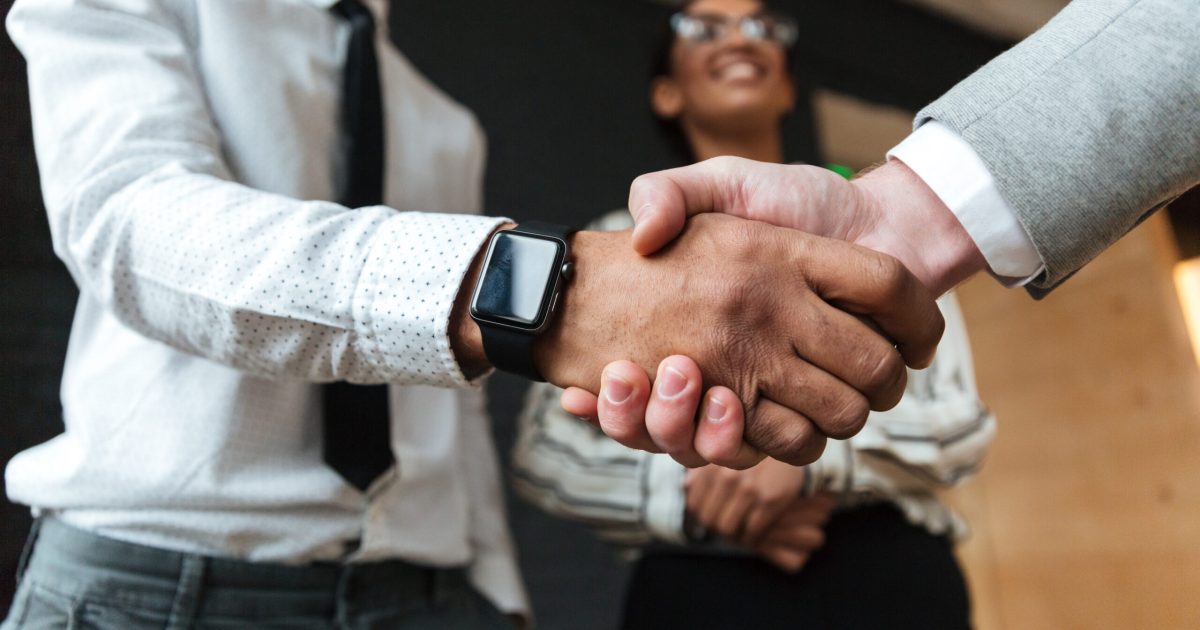 Cropped photo of handshake of young colleagues indoors coworking. Focus on hands.