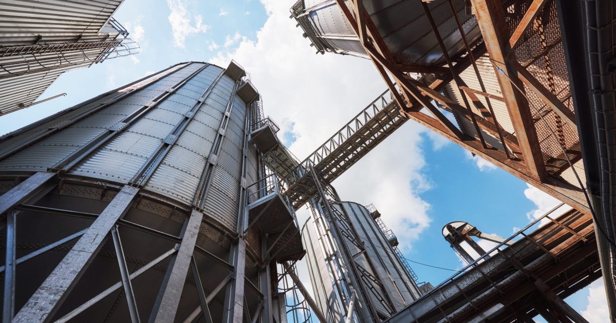 Agricultural Silos. Building Exterior. Storage and drying of grains, wheat, corn, soy, sunflower against the blue sky with white clouds.